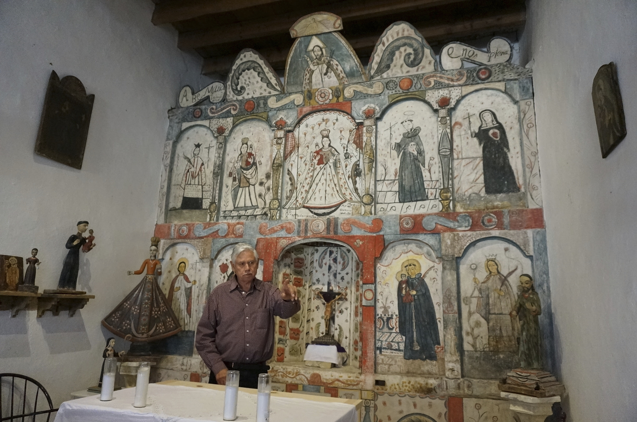 Master santero Felix Lopez – an artist trained in New Mexico's centuries-old tradition of religious sculpture and painting – speaks during an interview while standing in front of the 1810s reredo or altarpiece he cleaned and preserved in the Holy Rosary Mission Church in Truchas, New Mexico, Sunday, April 16, 2023.