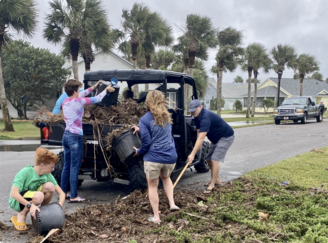 Youth and adults with Hurricane Helpers help clean up after a storm.