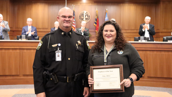 Image of Captain Jack Scarborough standing with Amy Elkins in the Board of Commissioners meeting room.