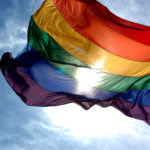 1280px-Rainbow_flag_and_blue_skies