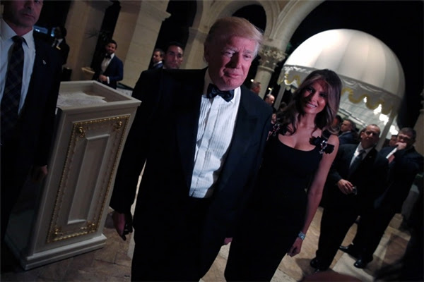 Đến 8g35, Donald Trump cùng vợ là Melania đến Mar-a-Lago và cùng dắt tay nhau bước vào sảnh tiệc. Ông Trump vô cùng lịch lãm trong bộ vest đen đơn giản và chiếc nơ bướm còn bà Melania thì lại hết sức sang trọng trong bộ đầm đen được trang trí nơ ở hai bên dây áo và điểm nhấn là một chiếc vòng kim cương lấp lánh trên tay bà.