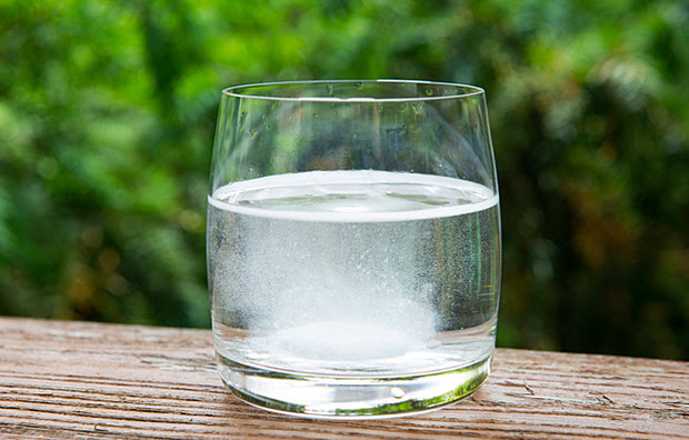 A glass of water with a dissolving effervescent tablet inside.