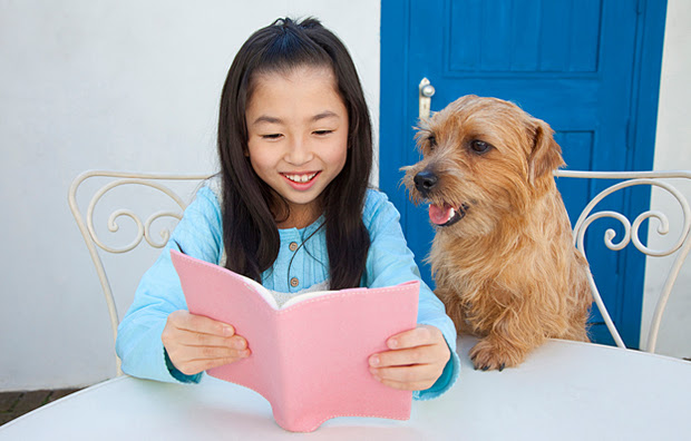A young girl reading to her dog.