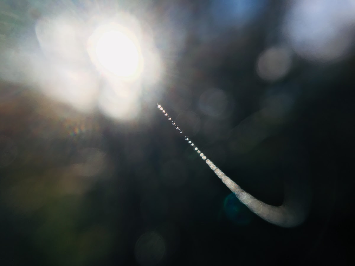 A blurred image of a droplet of water pointed toward a bright ball of light