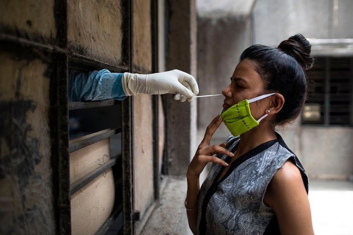 A health official collects a swab sample from a woman to test for coronavirus at a temporary free testing facility in New Delhi