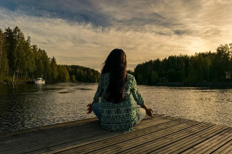 This shows a woman sitting peacefully by a lake
