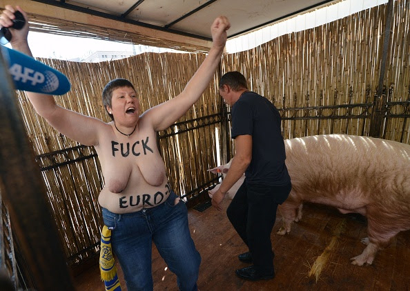 An activist of Ukrainian women movement Femen shouts slogan as she protests in the cage Funtik the 'psychic' pig in the Euro 2012 fanzone in Kiev on...