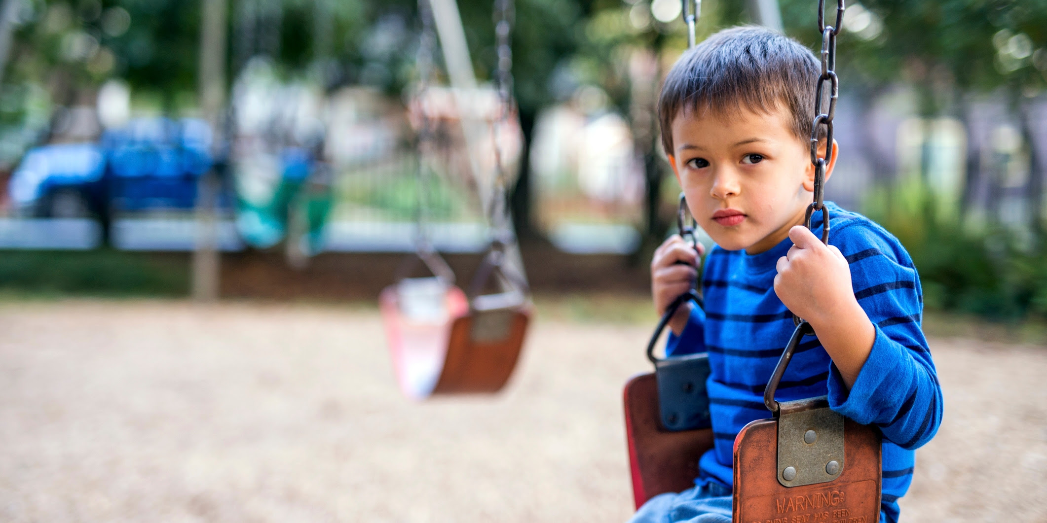 A young, sad child sitting on a swing