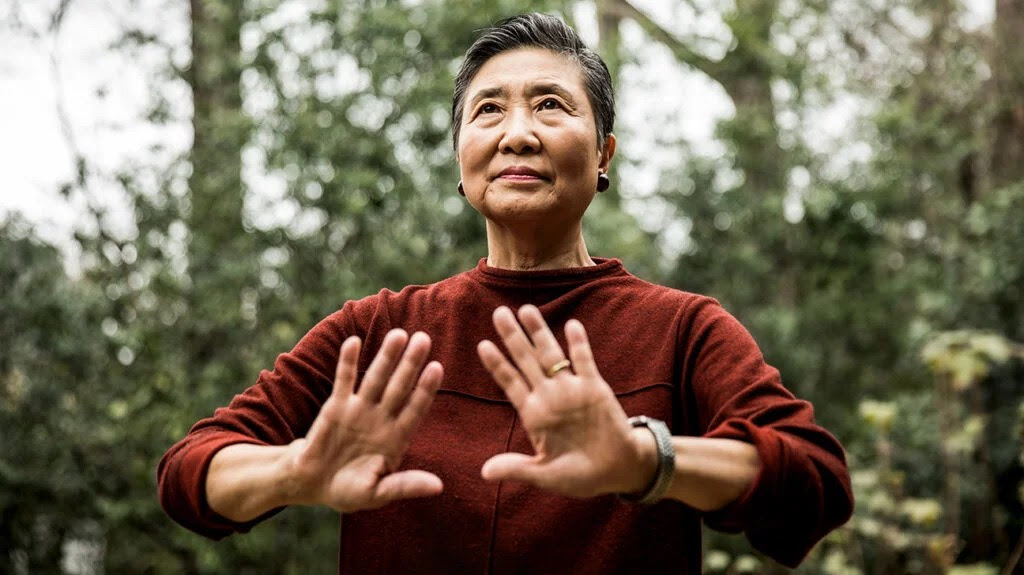 An older female adult practices Tai chi in nature outdoors