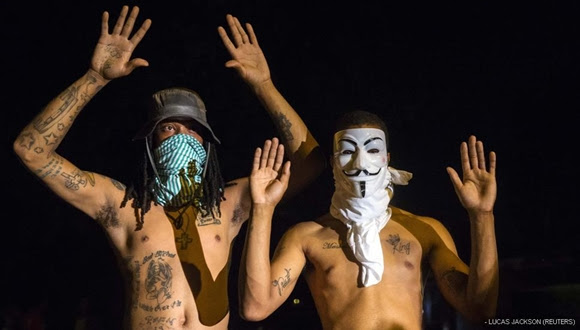Manifestantes levantan las manos delante de la Policía. Este gesto se ha convertido en el símbolo de las protestas aludiendo a Brown, que recibió seis disparos estando desarmado.