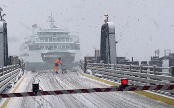 Person laying down salt on a vehicle transfer span at a ferry terminal