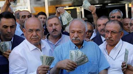 Hombres con dólares estadounidenses en sus manos frente a una oficina de cambio en Ankara, Turquía, el 14 de agosto de 2018