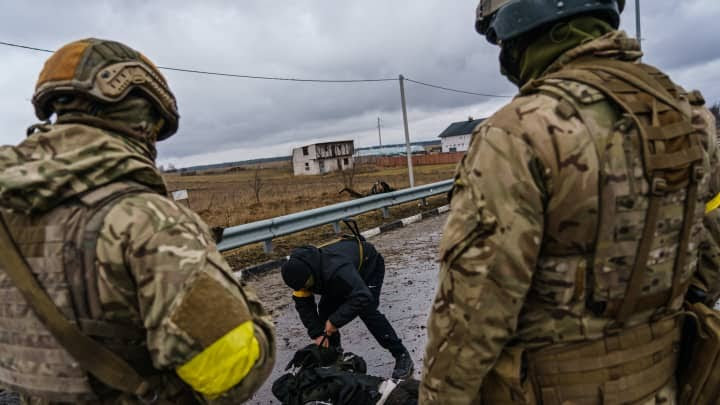 Russian forces in Ukraine have seen far more casualties than Moscow was expecting, analysts say. In this image, Ukrainian soldiers are salvaging equipment from the body of a dead Russian soldier after a Russian vehicle was destroyed by Ukrainian forces on March 3, 2022.