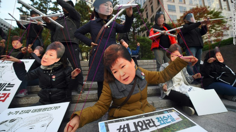 Protesters wearing masks of South Korean President Park Geun-Hye and her confidante Choi Soon-Sil perform before a candlelit rally in central Seoul on Saturday.