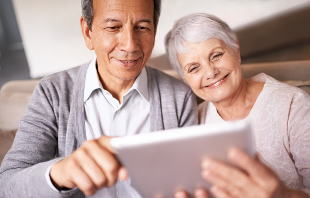 A senior couple taking a quiz on their digital tablet.