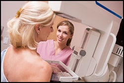 The figure above is a photograph showing a woman having a mammogram administered by a medical professional.