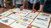 A group of researchers examines charts spread out on a desk. 