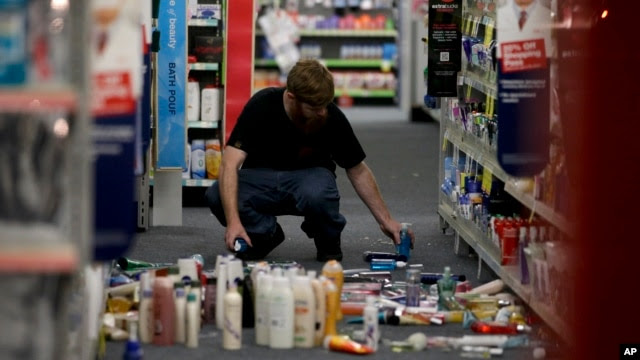 Một người đàn ông nhặt các vật bị rơi sau trận động đất tại 1 cửa hàng CVS, ở La Mirada, California, 28/3/2014