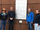 Photo of four people standing in front of tribal art