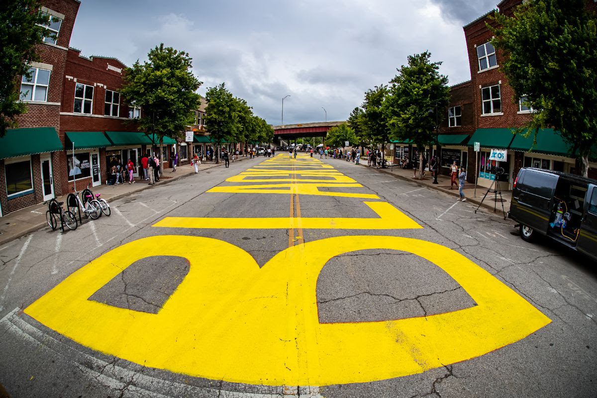 Fish-eye lens view of large painted letters on a city street that spell out “Black Lives Matter.”