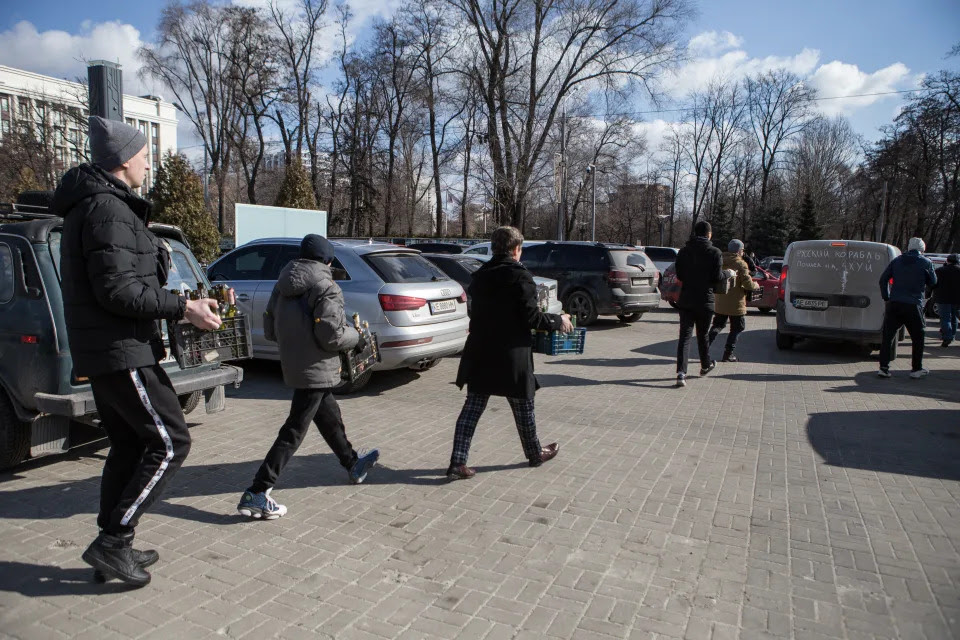 Locals at a park in Dnipro, Ukraine, carry crates of bottles.