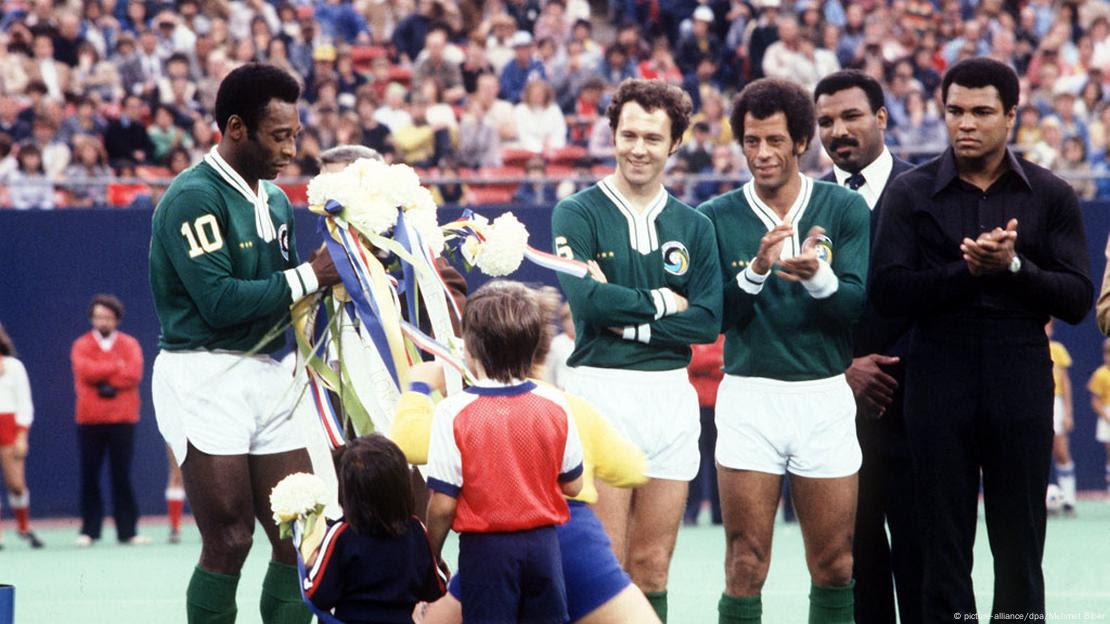 Pelé recebe flores de crianças em sua despedida do futebol, em 1977, ao lado de seus colegas de Cosmos, Carlos Alberto Torres e Franz Beckenbauer, e da lenda do boxe Muhammad Ali 