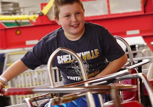 youth boy riding carnival ride with shelbyville shirt