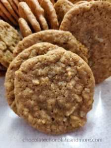 A brown cookie full of coconut with several other cookies stacked behind it