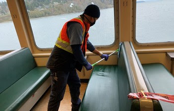 Photo of vessel crewmember wearing a mask and cleaning a booth