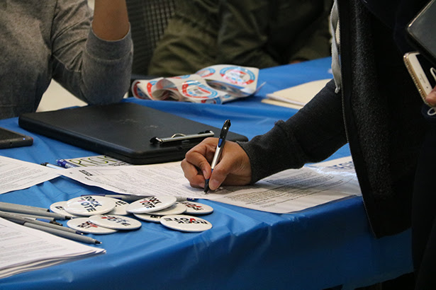 A closeup of a table with a Kean University student registering to vote.
