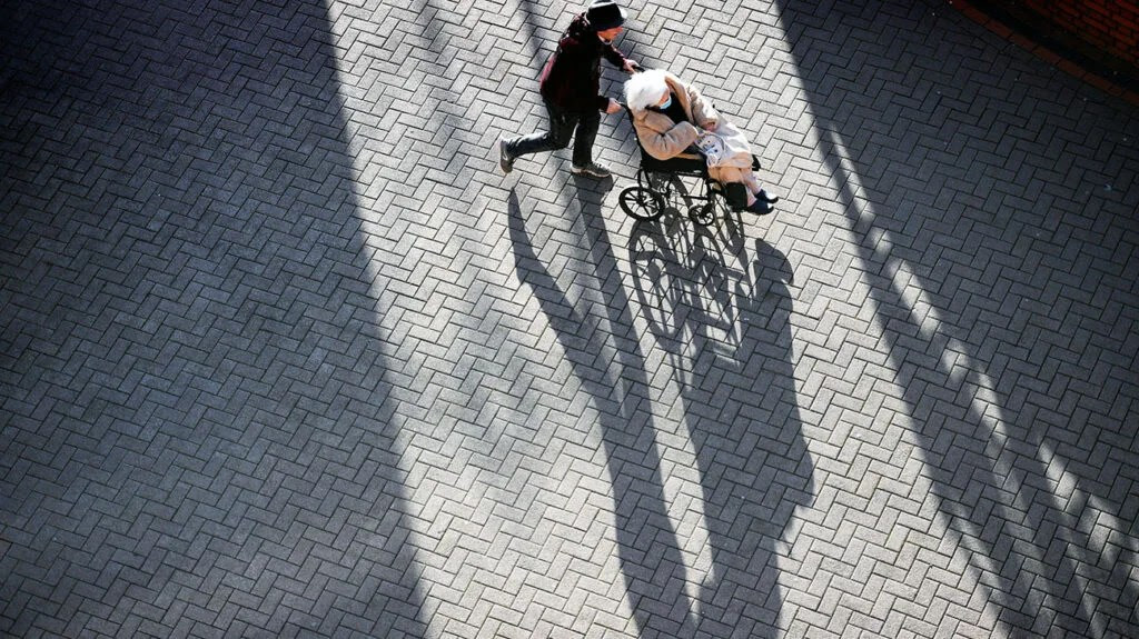 person pushing older person in wheelchair