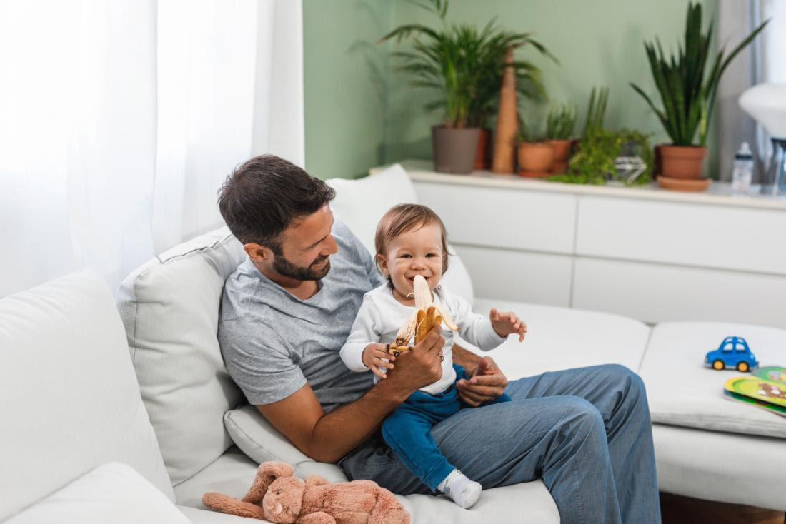 a person feeding baby a banana