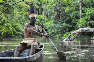 Indigenous man rowing in a canoe in the Amazon Rainforest in Brazil