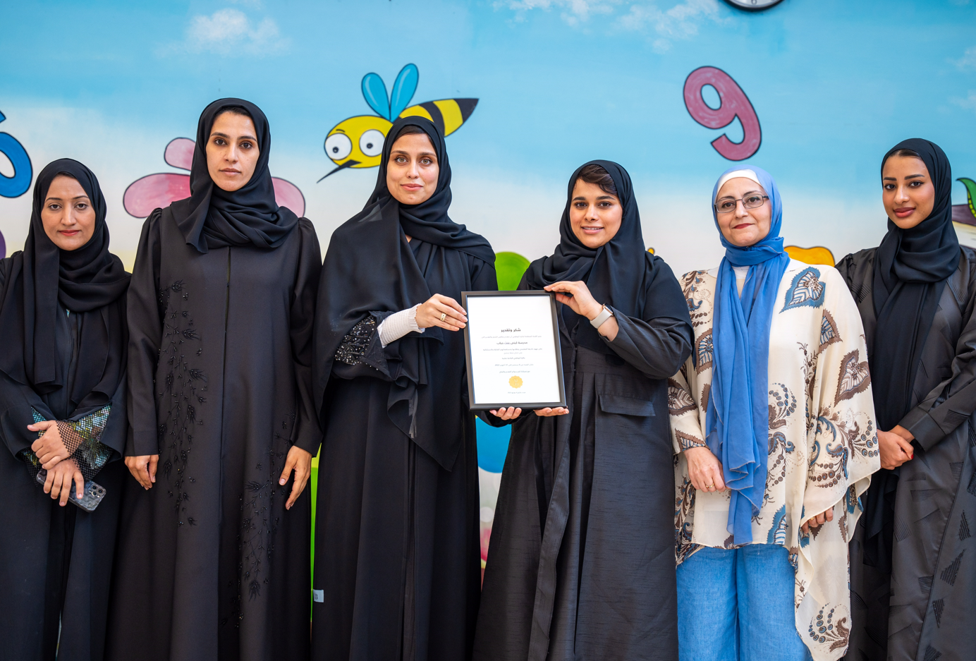 A group of women wearing black robes and holding a certificateDescription automatically generated with low confidence