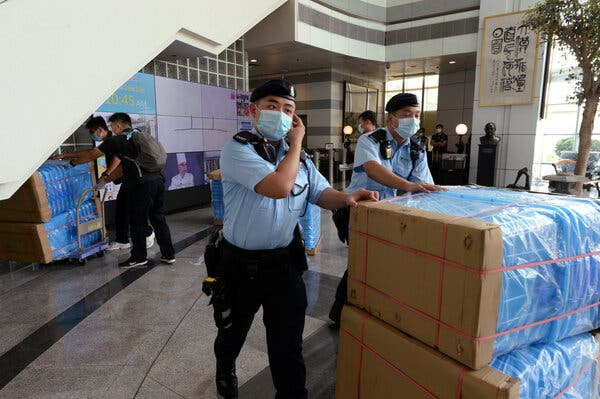 Police officers moving bundles of material at Apple Daily headquarters on Monday.