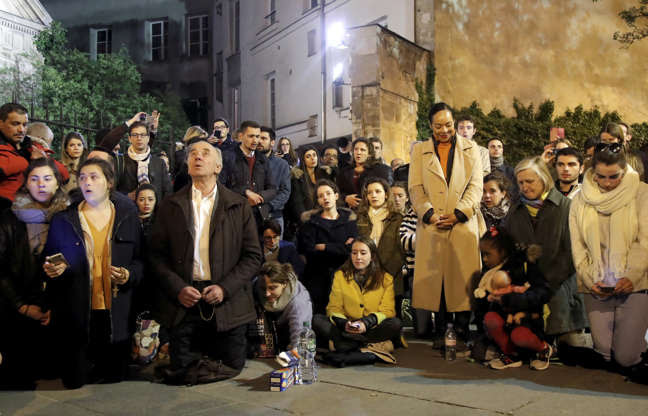 Slide 4 of 31: People pray and sing religious songs next to Notre Dame Cathedral after a fire broke out, in Paris, France April 15, 2019. REUTERS/Charles Platiau