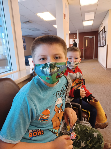 Photograph of two boys, Rowdy and Stetson Robinson, in a doctor/s office for their COVID vaccines.