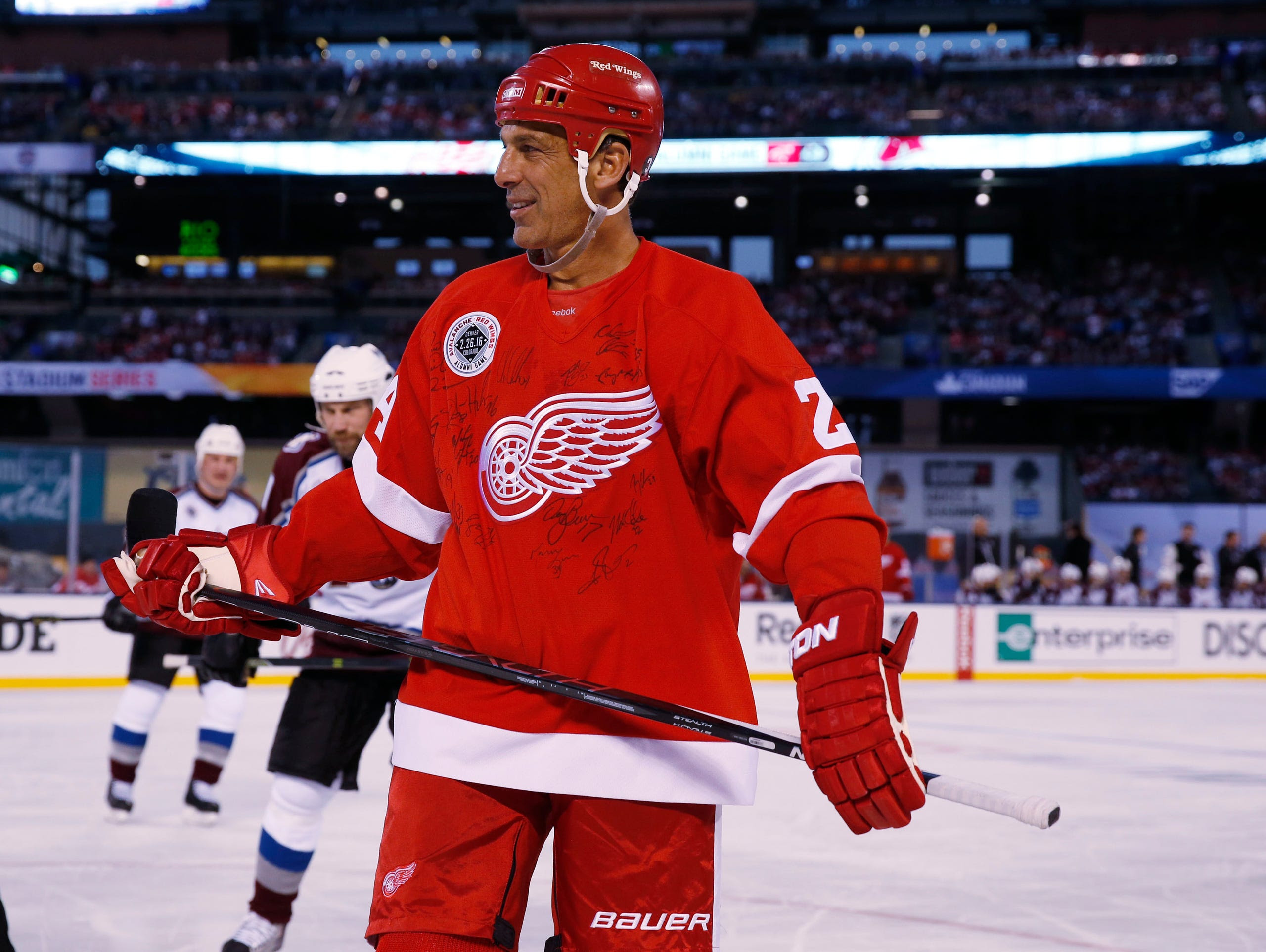Detroit Red Wings defenseman Chris Chelios wears a sweater signed by teammates against the Colorado Avalanche at Coors Field in Denver on Feb. 26, 2016.