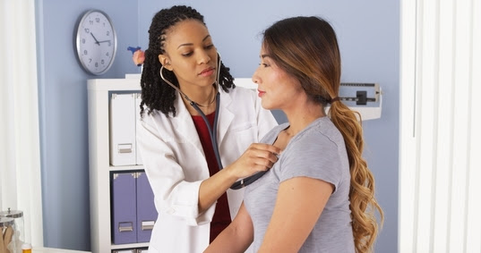 female doctor listening to female patients heart