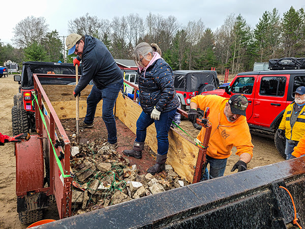 Earth Day cleanup volunteers bring trash to a dumpster.