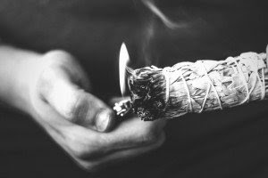 A hand lights a Stick of Sage on Fire