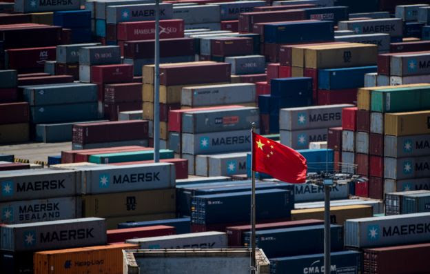Bandeira chinesa em meio a containeres em porto