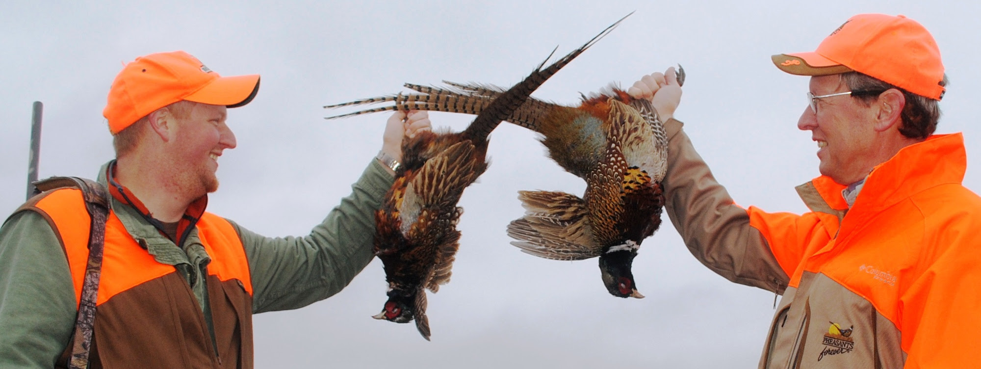 Jason Myers, a Farm Bill biologist who covers four counties working out of the Tuscola Conservation District, left, and Bill Vander Zouwen, Michigan Region representative for Pheasants Forever, display a couple of ring-necked pheasants they shot. Two hunters dressed in hunter jackets hold one pheasant each they shot in Lower Michigan.