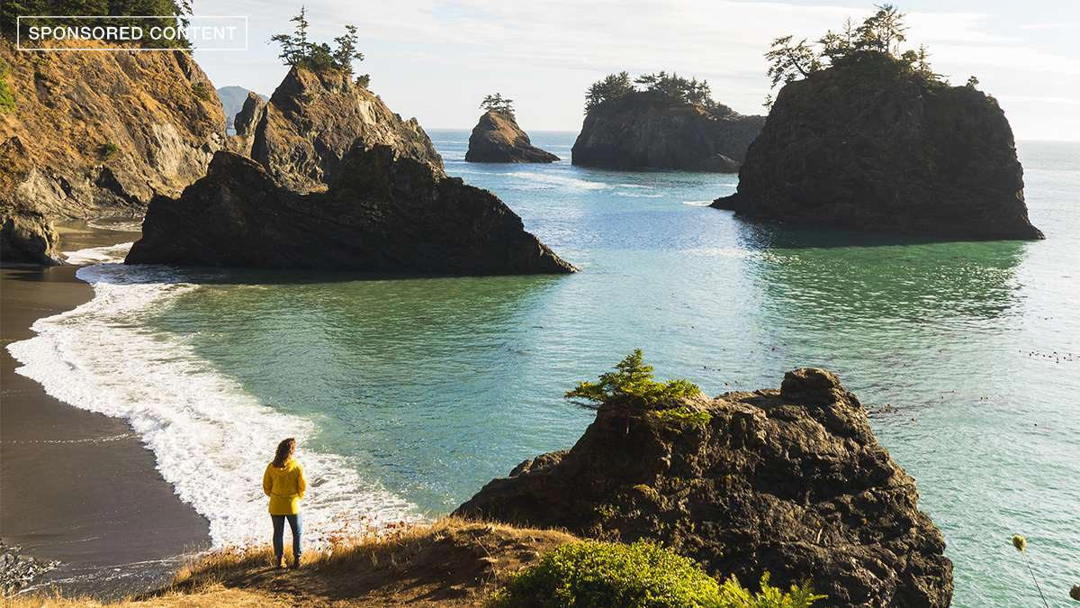 Une femme debout et face à la mer sur la côte de l'Oregon, USA.