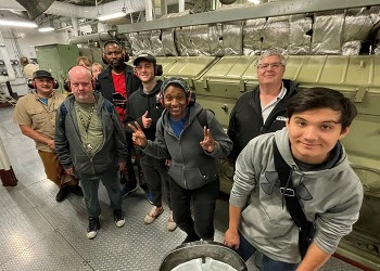 Several people posing for a photo in the engine room of a ferry
