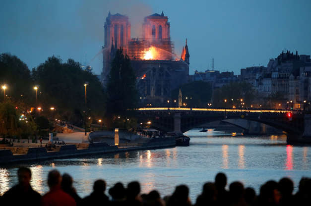 Slide 15 of 31: People watch as fire fighters douse flames of the burning Notre Dame Cathedral in Paris, France April 15, 2019. REUTERS/Charles Platiau - RC17DCBE9F60