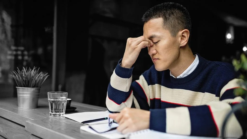 a man sitting at a table with his eyes closed