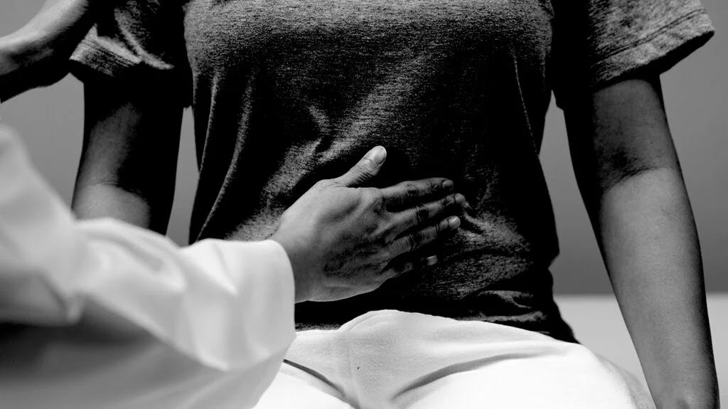 A healthcare professional touching a person's abdomen.