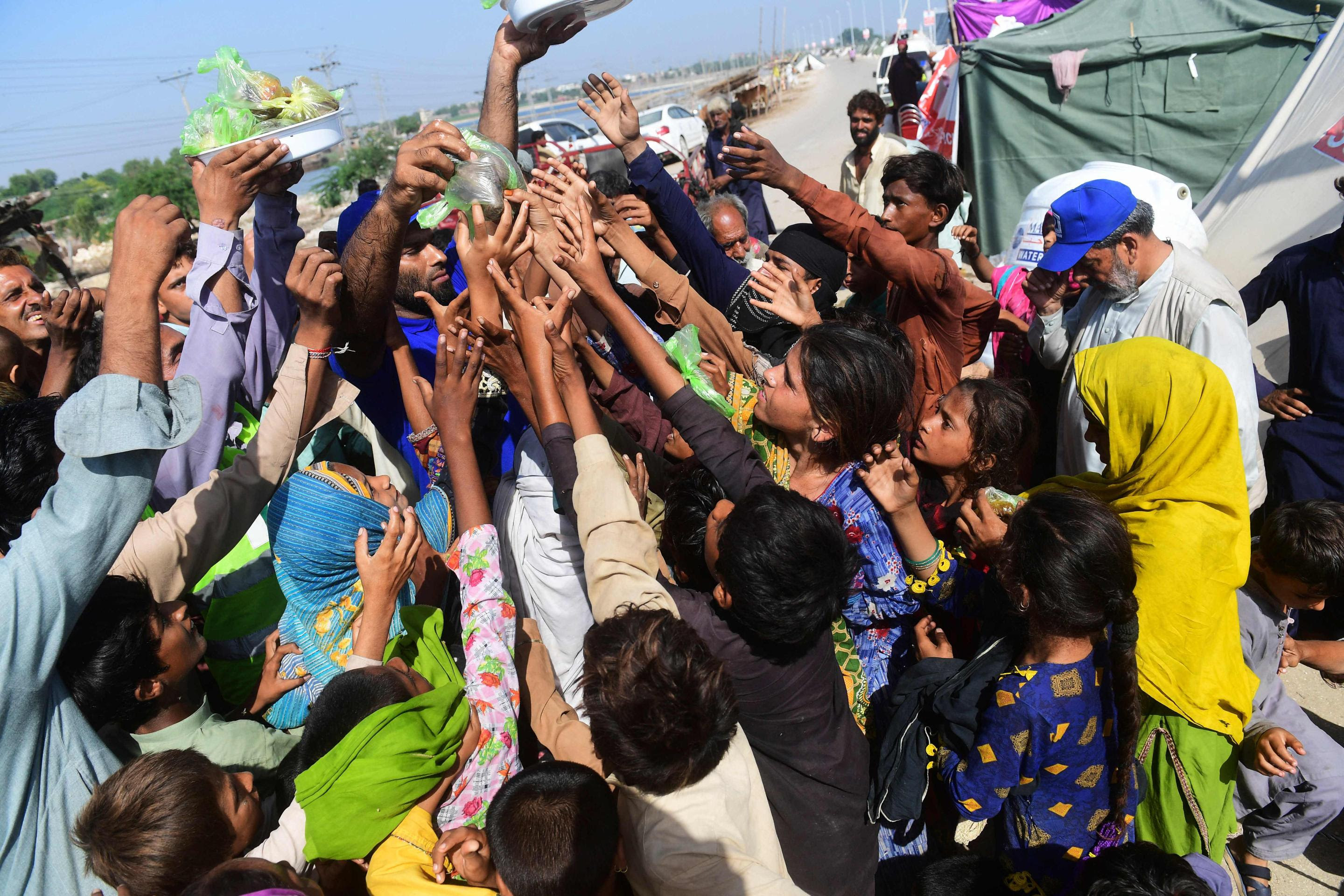 Volunteers distribute food bags to flood-affected children at a camp in Sukkur, Sindh province