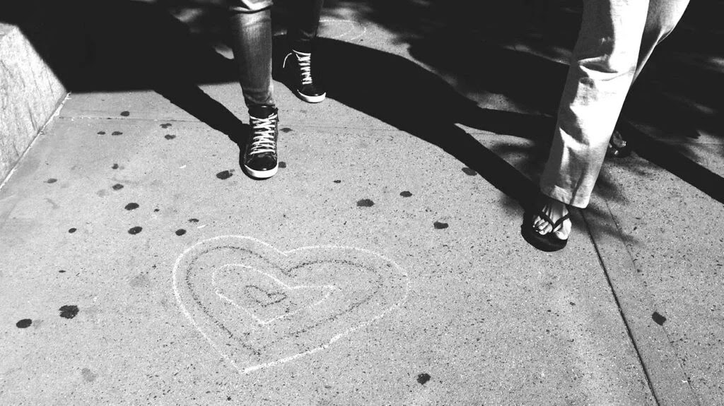 two people walking on a sidewalk covered with hearts drawn with chalk